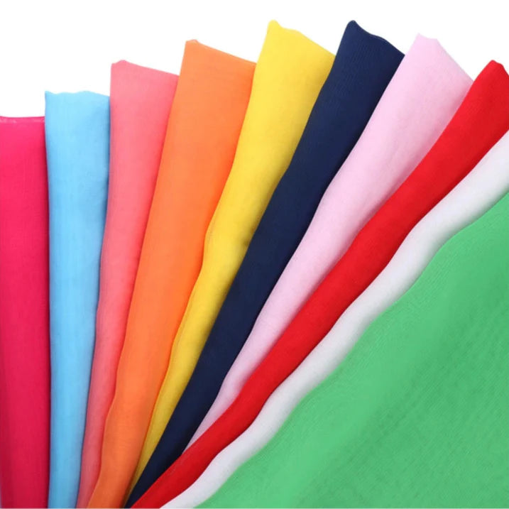 Un éventail de dix échantillons de tissu transparent Mousseline léger de Longan Craft France, comprenant du rose, du bleu, de l'orange, du jaune, du marine, du rose pâle, du rouge, du blanc et du vert en mousseline de polyester. Présentés sur un fond blanc.