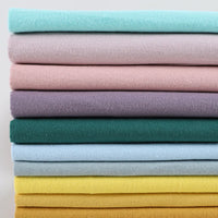 Une pile bien rangée de Flanelle de coton uni au mètre de Longon Craft France dans des couleurs unies assorties - bleu, rose, violet, vert, jaune, sarcelle - offre un tissu flanellette super doux pour des quilts d'automne douillets et des projets câlins.