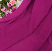 La Mousseline extensible au mètre de Longan Craft France, en polyester épais et extensible d'un rose vif, est drapée sur une surface, ornée dans le coin supérieur gauche de fleurs artificielles roses, violettes et blanches.