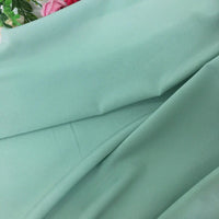 Gros plan sur la Mousseline extensible au mètre de Longan Craft France, une mousseline de polyester vert clair à la texture lisse et extensible. Ses plis souples et ses accents floraux la rendent idéale pour la confection de robes élégantes ou les projets créatifs.