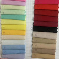 Des échantillons rectangulaires de Popeline de coton extensible au mètre-40S de Longan Craft France, teintée pour les chemises, les robes, les doublures et l'artisanat, sont disposés dans des tons pastels (à gauche) et rouges/neutres/tans (à droite) pour la sélection de la couture.