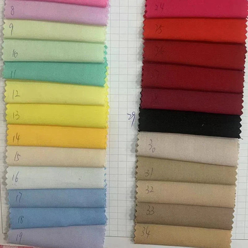 Des échantillons rectangulaires de Popeline de coton extensible au mètre-40S de Longan Craft France, teintée pour les chemises, les robes, les doublures et l'artisanat, sont disposés dans des tons pastels (à gauche) et rouges/neutres/tans (à droite) pour la sélection de la couture.