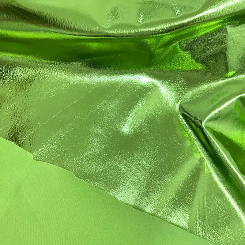 Un gros plan montre deux tissus verts de Longan Craft France : l'un est un tissu lamé brillant en polyester extensible avec une finition réfléchissante, l'autre est mat et lisse - tous deux présentés à plat avec des plis visibles. Idéal pour la couture, les projets créatifs et l'ameublement.