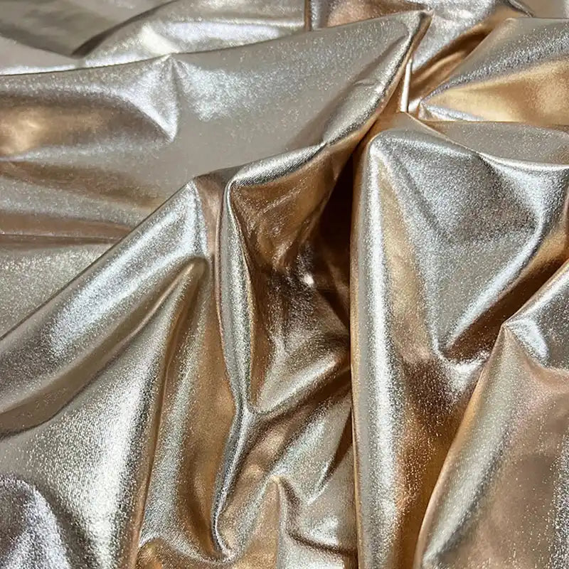 Gros plan sur le tissu lamé stretch au mètre de Longan Craft France, un polyester brillant dont les plis reflètent la lumière pour un effet brillant - parfait pour la couture, les loisirs créatifs, la tapisserie et les costumes de scène précieux.
