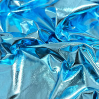 Gros plan sur le tissu lamé stretch au mètre de Longan Craft France, un tissu polyester bleu métallisé brillant avec des plis réfléchissant la lumière, idéal pour la couture, les loisirs créatifs, la tapisserie ou la création de vêtements de sport souples et de costumes de scène précieux.