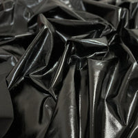 Gros plan sur le tissu lamé noir brillant stretch au mètre de Longan Craft France, montrant sa surface en polyester réfléchissant avec des plis irréguliers - idéal pour la couture, les loisirs créatifs, la tapisserie et les costumes de scène.