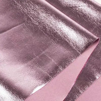 Gros plan sur le Tissu lamé stretch au mètre de Longan Craft France : tissu de polyester rose métallisé et brillant avec une finition lisse et lustrée, idéal pour la couture, les projets de bricolage et l'ameublement. On voit les plis qui mettent en valeur sa surface réfléchissante.