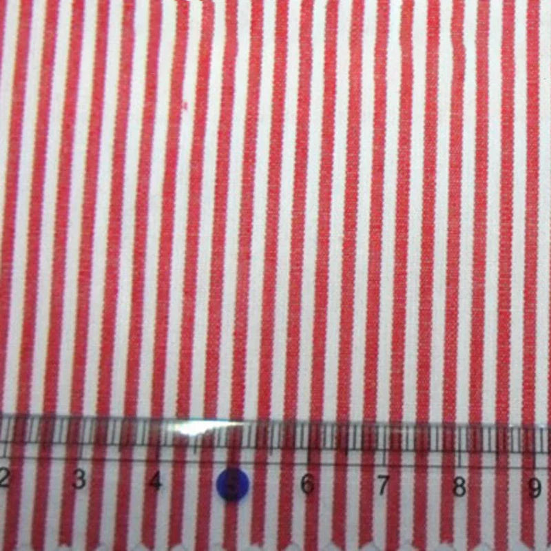Un gros plan du tissu en popeline de coton rayé au mètre de Longan Craft France montre des rayures rouges et blanches teintées dans la masse, avec une règle en bas marquant 4 à 10 cm. Popeline 100% coton, idéale pour les chemises, les robes et les nappes.