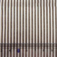 Gros plan sur des rayures teintes au fil sur un tissu en popeline de coton rayé au mètre de Longan Craft France (Tissu en popeline de coton rayé au mètre) ; alternance de rayures brunes et blanches avec une règle transparente indiquant 1 à 10 cm en bas.