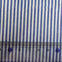 Un gros plan du tissu en popeline de coton rayé au mètre de Longan Craft France montre des rayures bleues et blanches teintes au fil avec une règle transparente (5-10 cm) pour l'échelle.