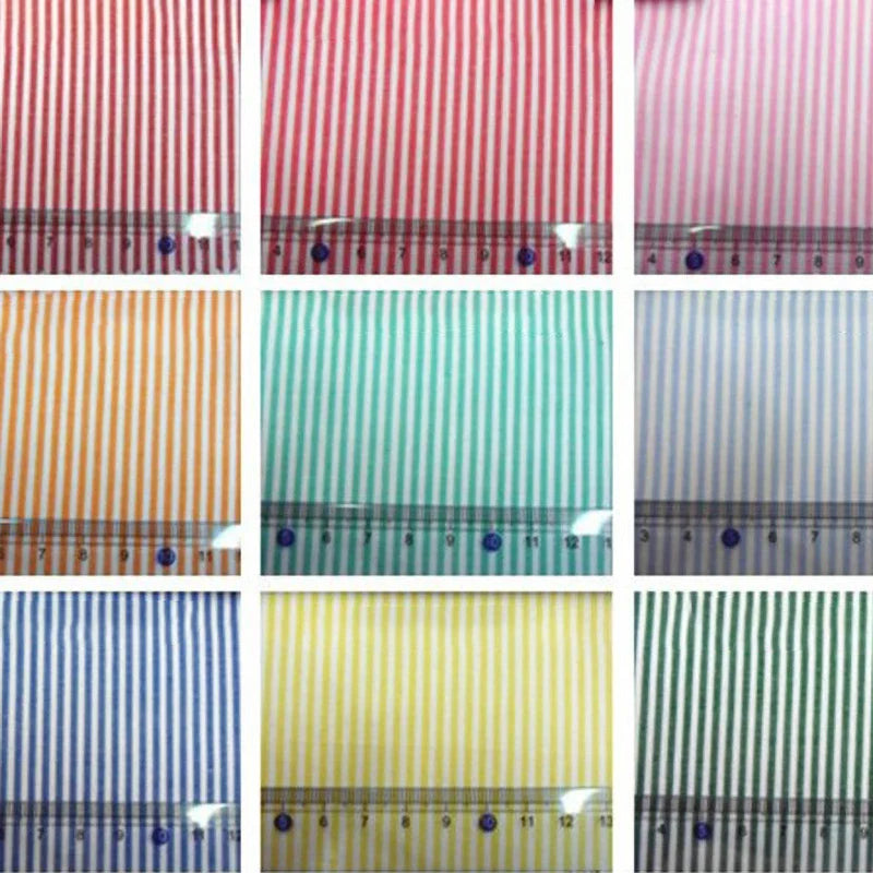 Neuf échantillons de popeline de coton rayée teintée au fil de Longan Craft France, présentés avec une règle pour l'échelle. Ces tissus 100 % coton en rouge, rose, orange, vert, bleu, jaune et mélanges vibrants sont parfaits pour les chemises, les robes et les nappes.