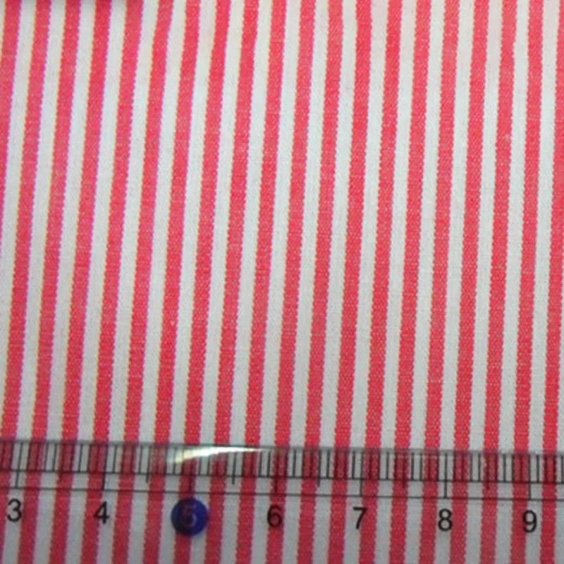 Gros plan sur le Tissu en popeline de coton rayé de Longan Craft France, montrant des rayures roses et blanches 100 % coton teintées dans la masse, avec une règle transparente (3-9 cm) pour l'échelle. Idéal pour les chemises, les robes et les nappes.