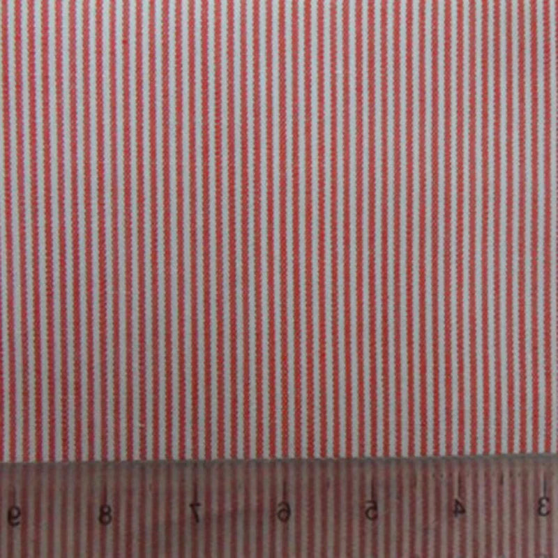 La popeline tissée unie rayée de Longan Craft France, en coton léger à rayures rouges et blanches, est parfaite pour chemises, robes et nappes. Une règle transparente posée au bord montre les mesures en centimètres.