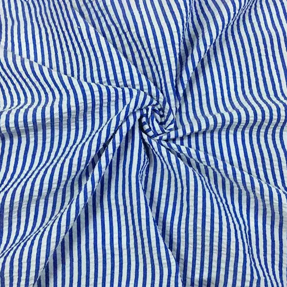 Le Seersucker rayé au mètre bleu et blanc de Longan Craft France est froncé et torsadé au centre, créant un motif en spirale avec une texture et des plis visibles - parfait pour l'été avec son mélange de polyester et de coton.