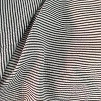 Un gros plan du Seersucker rayé au mètre de Longan Craft France montre ses rayures noires et blanches ondulées, mettant en valeur les plis uniques et la texture légère du polyester-coton - parfait comme tissu seersucker pour l'été.