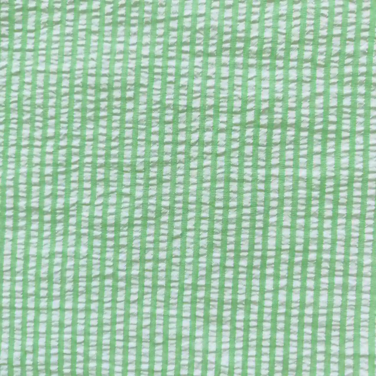 Un gros plan de Seersucker rayé au mètre de Longan Craft France montre un tissu doux et fibreux en polyester-coton avec des rayures verticales et horizontales vert clair formant un quadrillage - idéal tissu seersucker léger pour l'été.
