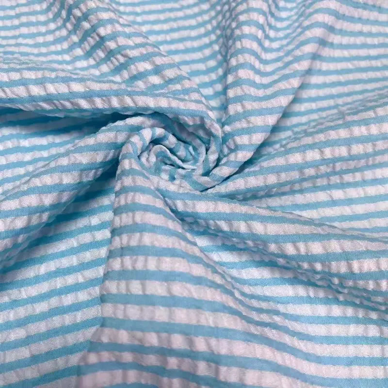 Un gros plan du seersucker rayé au mètre de Longan Craft France montre sa texture rayée colorée en polyester-coton torsadée en spirale, soulignant l'aspect froncé et la légèreté estivale de ce tissu seersucker pour l'été.