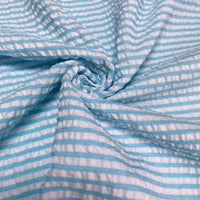 Un gros plan du seersucker rayé au mètre de Longan Craft France montre sa texture rayée colorée en polyester-coton torsadée en spirale, soulignant l'aspect froncé et la légèreté estivale de ce tissu seersucker pour l'été.