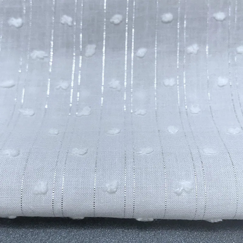 Un gros plan du Voile plumetis au mètre de Longan Craft France montre un voile de coton blanc suisse à pois avec des rayures verticales transparentes et des points en relief, drapé à plat - parfait pour la décoration intérieure, la couture et les loisirs créatifs.
