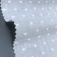 Gros plan sur le Voile plumetis au mètre de Longan Craft France - un voile de coton blanc suisse à pois avec des points texturés et des bords coupés en zigzag, légèrement transparent, idéal pour la couture, les projets créatifs et la décoration d'intérieur.