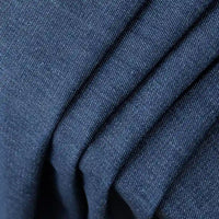 Gros plan sur le Tissu en jean coton lavé 14,5 oz de Longan Craft France : denim bleu foncé de première qualité avec un tissage finement texturé et des mouchetures blanches, présenté en couches avec des plis parallèles. Idéal pour les jeans et disponible au mètre.