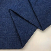 Gros plan sur le tissu en jean coton lavé 14,5 oz au mètre de Longan Craft France en bleu foncé, soigneusement plié pour mettre en valeur sa texture et son tissage riches sur un fond clair, idéal pour la fabrication de jeans durables ou comme tissu épais denim noir.