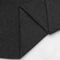 Gros plan sur le tissu en jean coton lavé 14,5 oz au mètre de Longan Craft France - un denim noir épais de première qualité à la texture lisse et subtilement mouchetée, présenté en couches sur un fond clair.