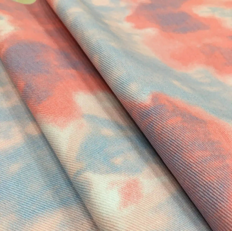 Gros plan sur le Tissu denim en coton tie-dye au mètre de Longan Craft France : denim coloré de 10 oz avec une texture nervurée en rose pastel, bleu et blanc. Idéal pour une décoration intérieure élégante ou des vêtements en jean uniques.