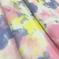 Gros plan sur le tissu tie-dye en coton 10oz de Longan Craft France, vendu au mètre, qui présente un effet aquarelle dans des tons doux de rose, jaune, bleu et blanc - idéal pour la décoration ou pour des vêtements en denim uniques.