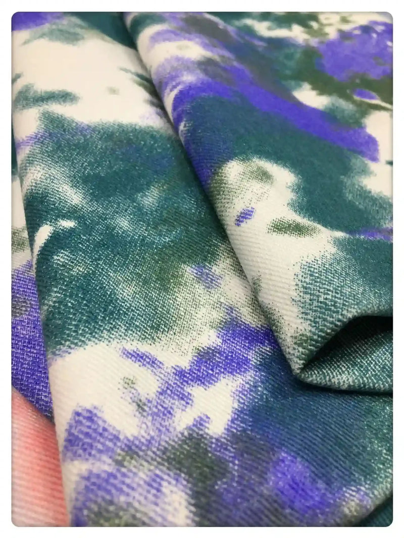 Gros plan sur le Tissu denim en coton tie-dye au mètre de Longan Craft France, un tissu denim coloré de 10 oz en vert, violet et blanc - idéal pour une décoration intérieure unique ou des vêtements en jean personnalisés.
