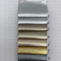 Huit échantillons rectangulaires de tissu lamé métallisé froissé au mètre par Longan Craft France, dans des tons métalliques allant de l'argent et de l'or au beige et au bronze, disposés verticalement (1-8), chacun avec une finition brillante et réfléchissante.