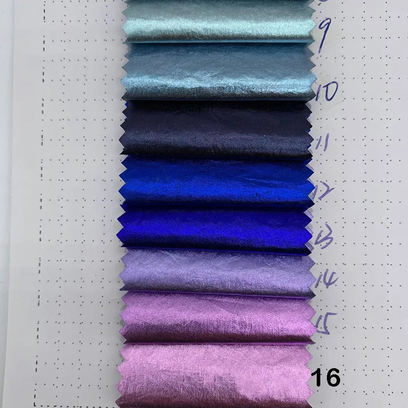 Dix échantillons de tissu bleu, violet et rose métallisé - Tissu lamé métallisé froissé de Longan Craft France - sont disposés verticalement sur un fond blanc pointillé, avec des numéros écrits à la main à côté de chaque échantillon.