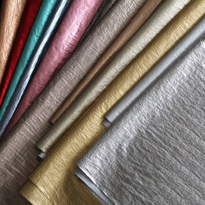 Gros plan sur le tissu lamé métallisé froissé de Longan Craft France en or, argent, beige, rose, sarcelle, rouge et mauve - parfait pour la couture créative et l'artisanat - disposé en diagonale sur l'image.