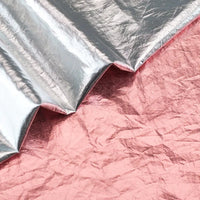 Une feuille de Tissu lamé métallisé froissé de Longan Craft France recouvre partiellement une feuille métallique rose, toutes deux présentant des textures froissées distinctes, idéales pour la couture et l'artisanat créatif.