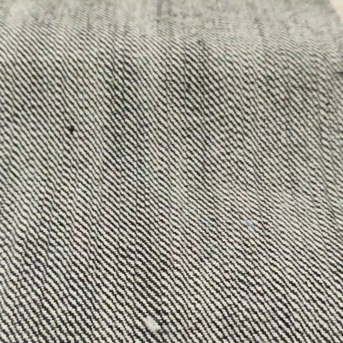 Gros plan sur le tissu en jean selvedge 16,5 oz de Longan Craft France - 100 % coton denim lourd - qui présente une texture et un tissage détaillés à rayures diagonales grises et blanches.