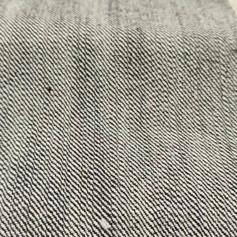 Gros plan sur le tissu en jean selvedge 16,5 oz de Longan Craft France - 100 % coton denim lourd - qui présente une texture et un tissage détaillés à rayures diagonales grises et blanches.