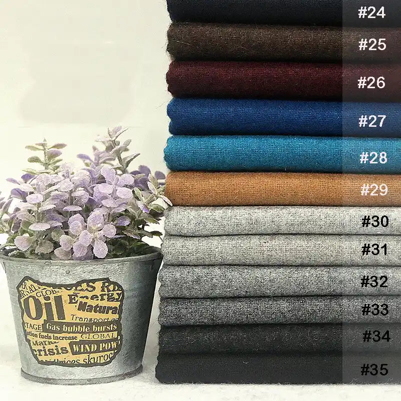 Une pile de tissu flanelle en laine et polyester de Longon Craft France dans des couleurs unies (#24-#35) est disposée à côté d'un pot de lavande en métal, mettant en valeur ce confortable textile d'intérieur parfait pour l'automne.