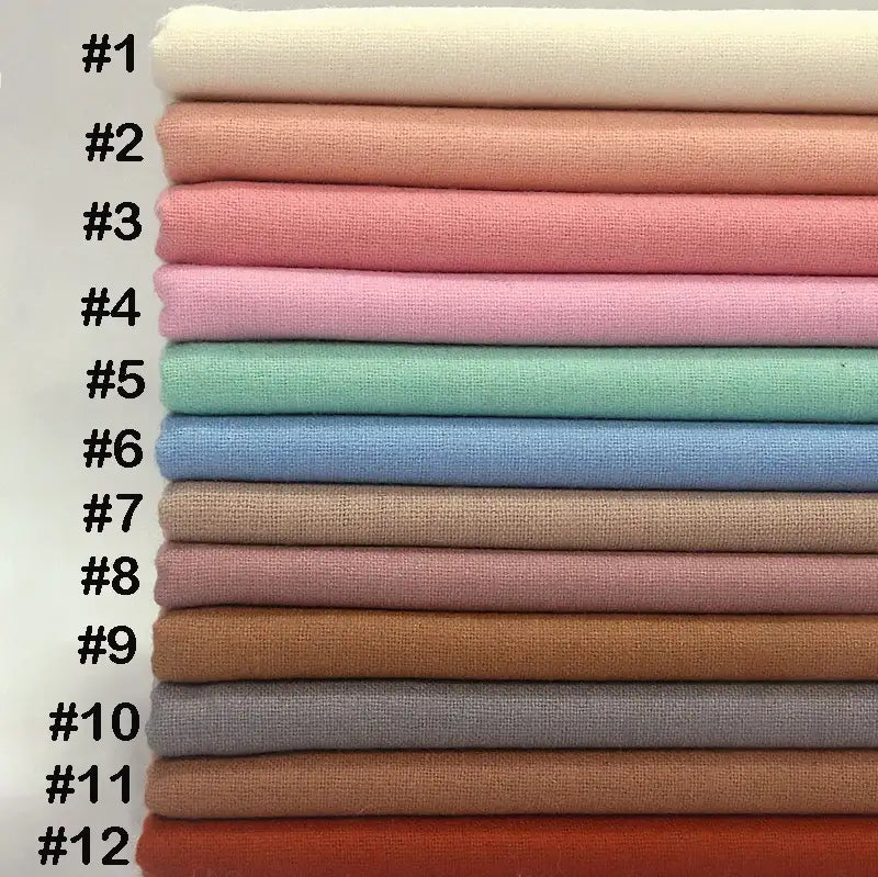 Une pile de douze pièces de tissu flanelle en laine au mètre de Longon Craft France dans des couleurs unies allant du blanc (#1) au rouge-orange (#12), idéal pour les vêtements d'hiver ou le textile d'intérieur, fabriqué avec de la laine et du polyester pour le confort de l'automne.